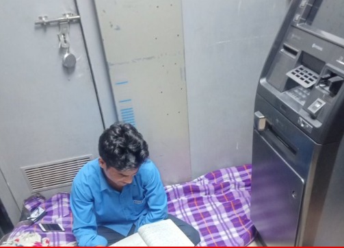 security guard studying by sitting near atm